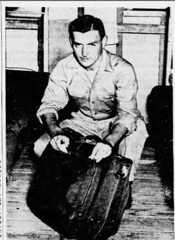 Sgt. Michael L. Reardon kneeling on a train platform, packing a duffel bag, 1945